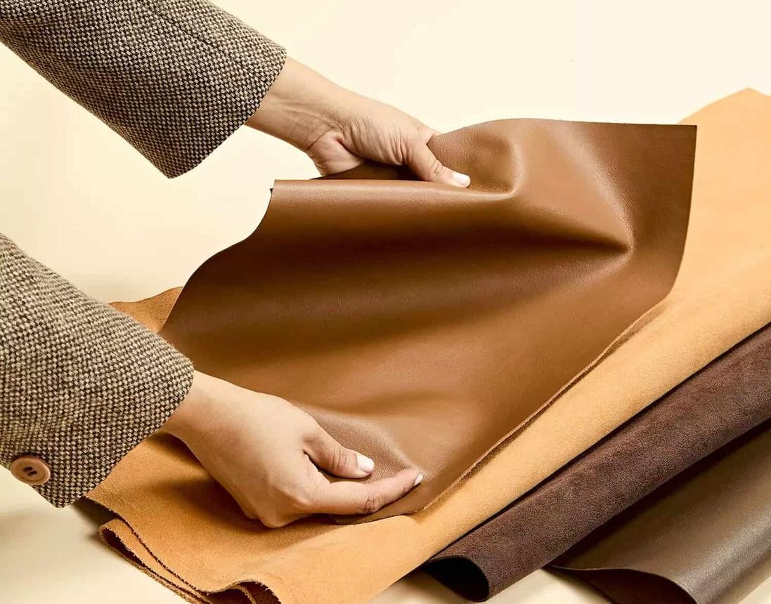 Hands examining swatches of brown vegan leather