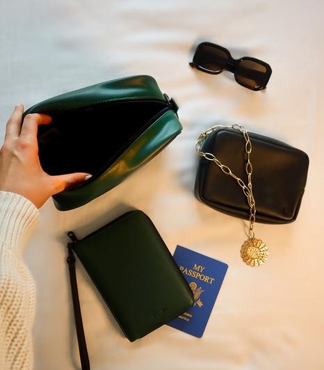 Green and black vegan leather handbags with sunglasses and a passport